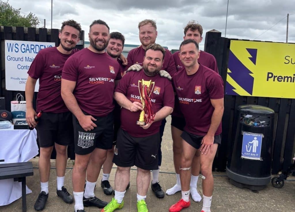 7 men in purple football kits, with a cup